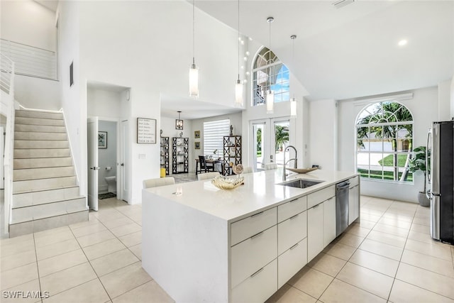 kitchen featuring sink, high vaulted ceiling, appliances with stainless steel finishes, an island with sink, and white cabinets