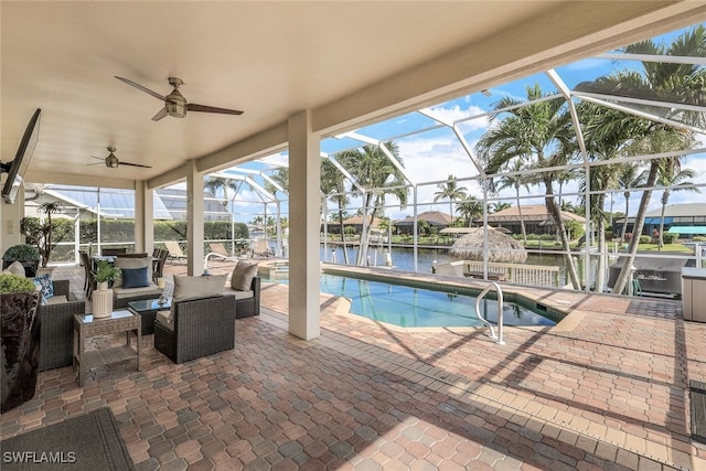 view of pool with ceiling fan, glass enclosure, an outdoor living space, a water view, and a patio area