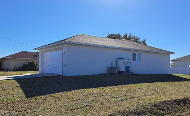 back of property featuring cooling unit, a garage, and a yard