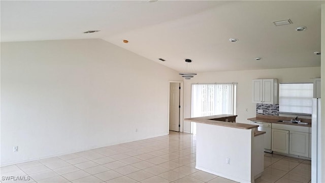 kitchen with vaulted ceiling, light tile patterned floors, dishwasher, and decorative backsplash