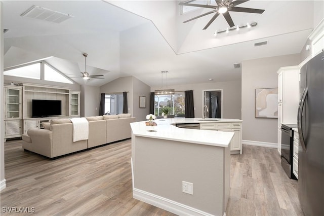 kitchen with vaulted ceiling, light hardwood / wood-style flooring, an island with sink, stainless steel appliances, and white cabinets