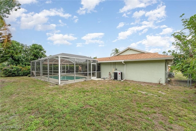 rear view of house with a yard, cooling unit, and glass enclosure