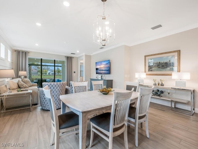 dining area featuring ornamental molding, plenty of natural light, a notable chandelier, and light hardwood / wood-style floors