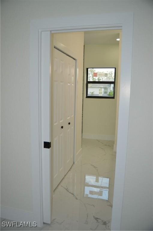 hall featuring marble finish floor and baseboards