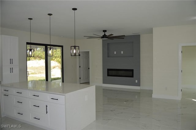 kitchen featuring a large fireplace, a center island, hanging light fixtures, and white cabinets