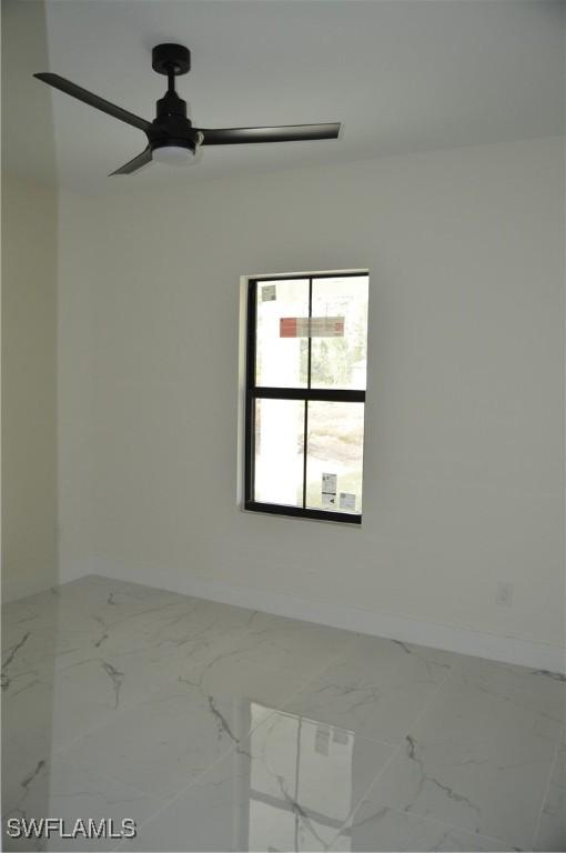 unfurnished room featuring marble finish floor, baseboards, and a ceiling fan