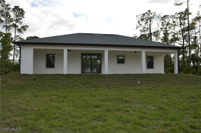 back of property featuring ceiling fan and a lawn