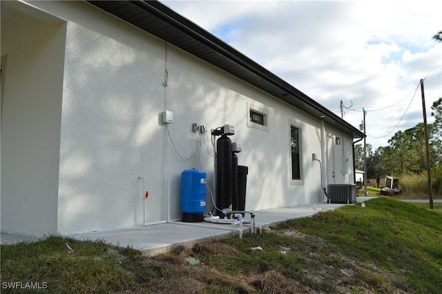 view of side of home with a yard, cooling unit, and a patio area