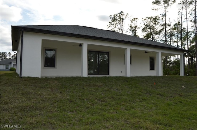 rear view of property featuring a lawn and ceiling fan