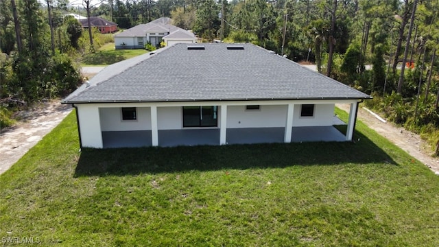 back of property featuring a yard, roof with shingles, and stucco siding