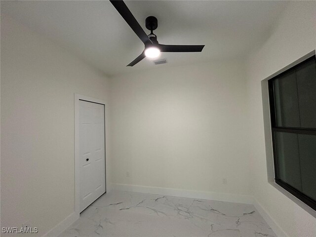 spare room with a ceiling fan, marble finish floor, visible vents, and baseboards