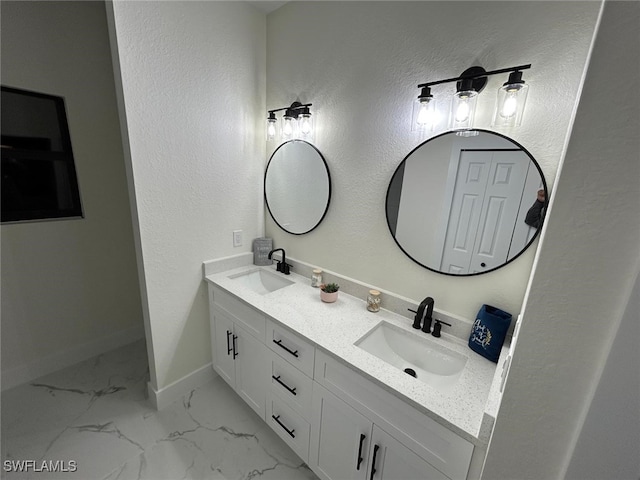 bathroom featuring double vanity, marble finish floor, baseboards, and a sink