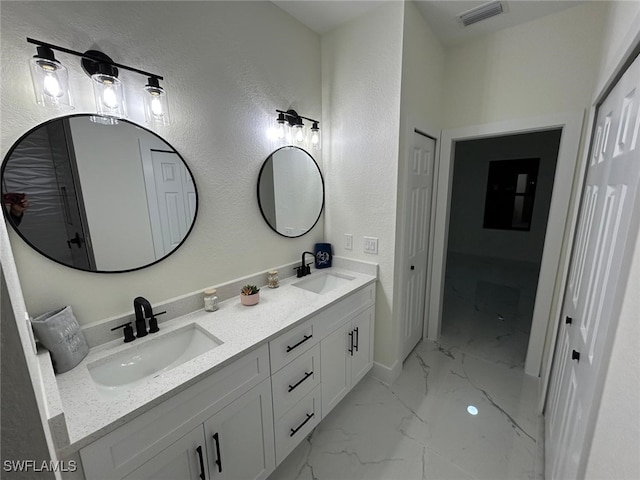 bathroom featuring marble finish floor, visible vents, a sink, and double vanity