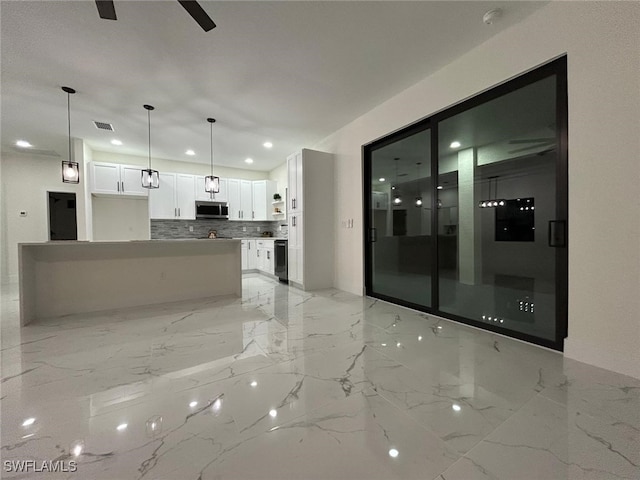 kitchen featuring marble finish floor, tasteful backsplash, stainless steel microwave, visible vents, and white cabinetry