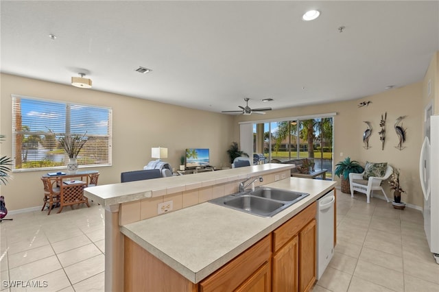 kitchen featuring light tile patterned flooring, white appliances, sink, and a center island with sink