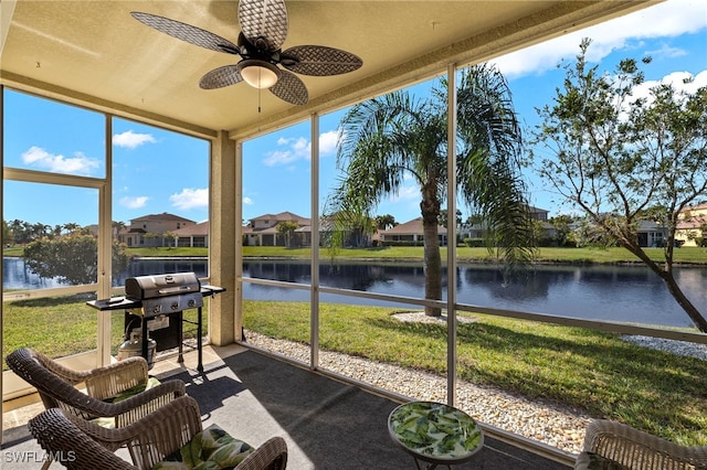 sunroom with ceiling fan and a water view