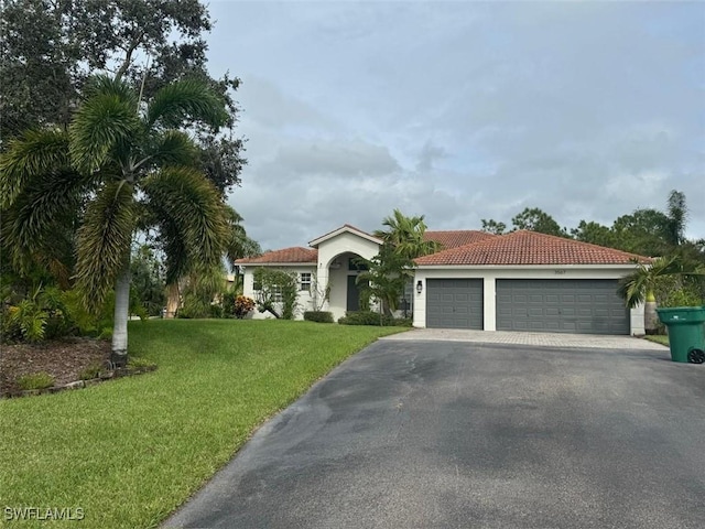 mediterranean / spanish house with a garage and a front lawn