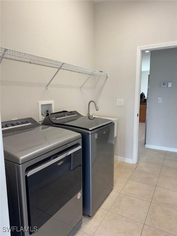 laundry area with light tile patterned floors and washing machine and dryer