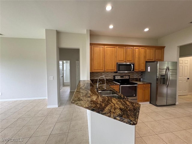 kitchen featuring sink, dark stone countertops, kitchen peninsula, stainless steel appliances, and decorative backsplash