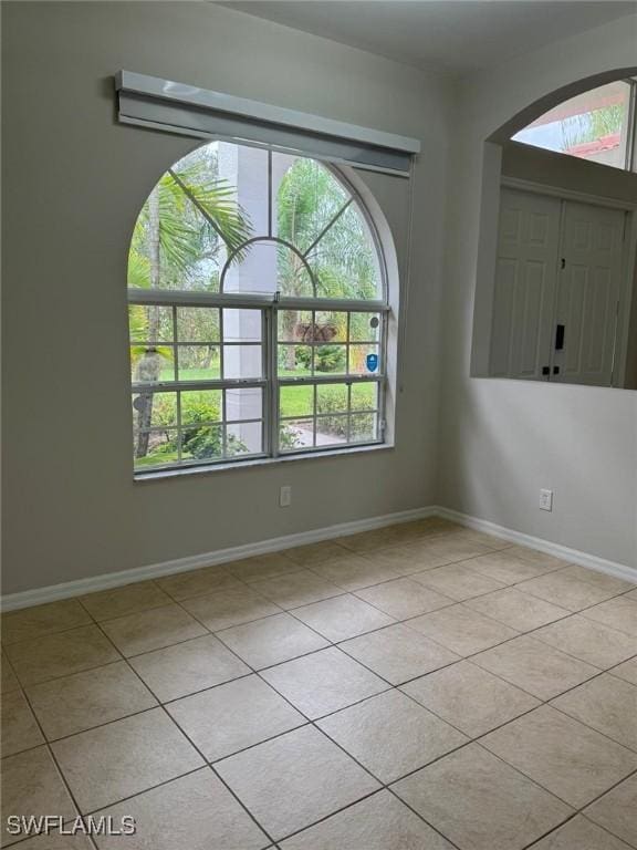 empty room featuring light tile patterned floors and plenty of natural light