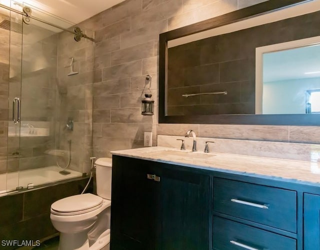 full bathroom featuring toilet, tile walls, enclosed tub / shower combo, and vanity