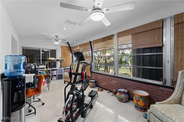 workout room with brick wall, light tile patterned floors, and ceiling fan