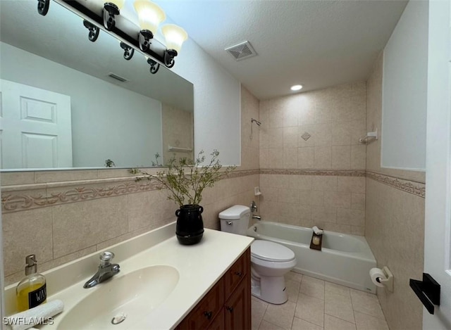 full bathroom with tiled shower / bath, tile patterned flooring, vanity, tile walls, and toilet