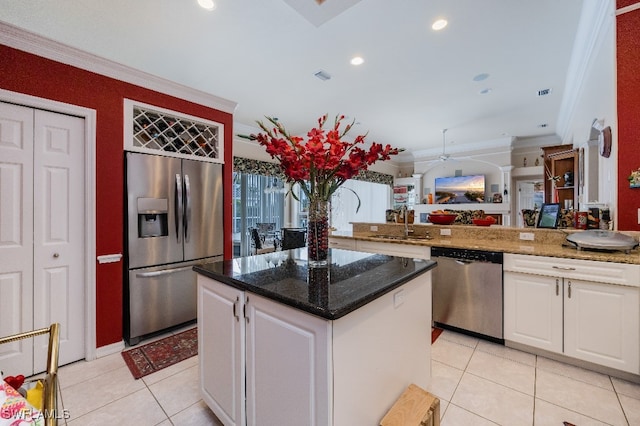 kitchen featuring appliances with stainless steel finishes, light tile patterned flooring, white cabinetry, and ornamental molding