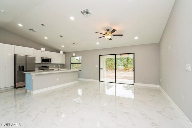 kitchen featuring lofted ceiling, decorative light fixtures, white cabinetry, stainless steel appliances, and a center island with sink