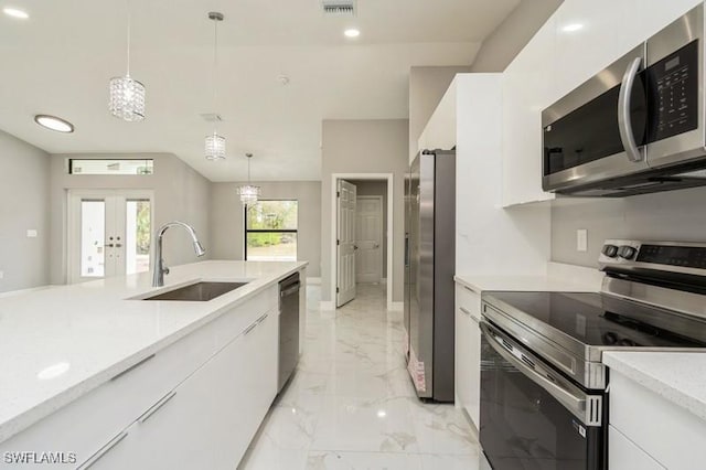 kitchen with decorative light fixtures, sink, white cabinets, and appliances with stainless steel finishes