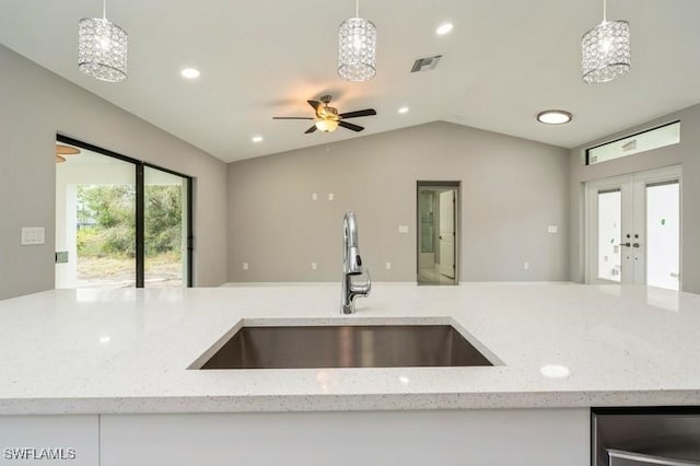 kitchen with lofted ceiling, light stone countertops, pendant lighting, and sink