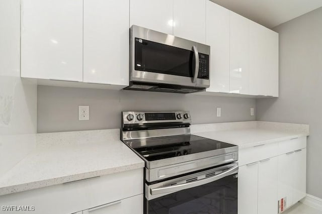 kitchen with appliances with stainless steel finishes, white cabinetry, and light stone countertops