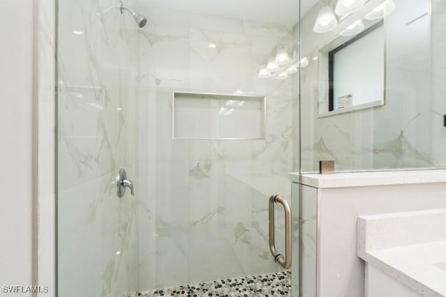 bathroom featuring a shower with shower door and vanity