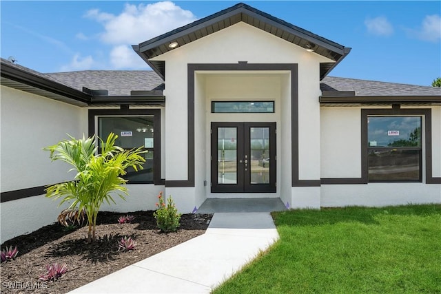 view of exterior entry featuring french doors and a yard