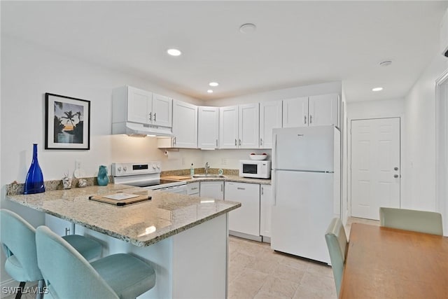 kitchen featuring sink, white cabinets, white appliances, and kitchen peninsula