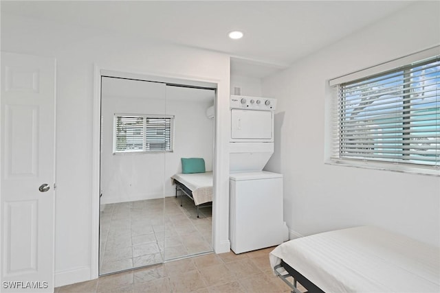 bedroom with a closet, stacked washer / drying machine, and multiple windows