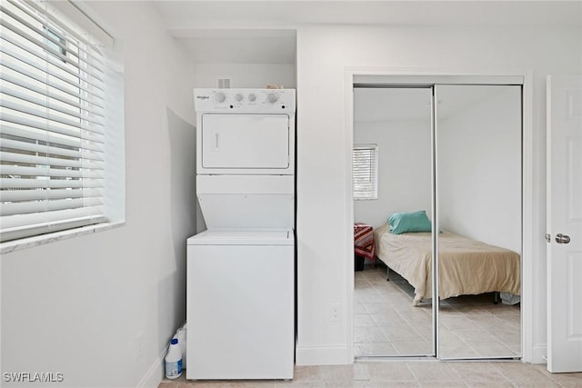 washroom featuring stacked washer and dryer and a healthy amount of sunlight