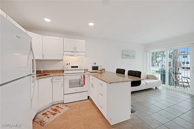 kitchen with a breakfast bar area, kitchen peninsula, white appliances, light stone countertops, and white cabinets