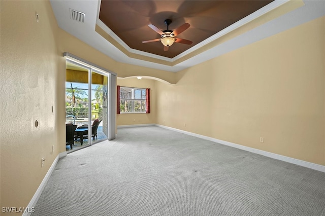 empty room with ornamental molding, light colored carpet, ceiling fan, and a tray ceiling