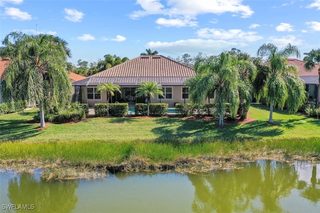 back of house featuring a water view, a yard, and glass enclosure