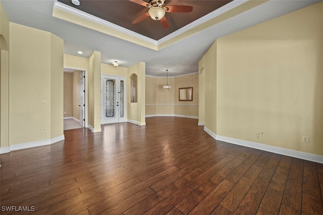 empty room with dark wood-type flooring, ceiling fan, ornamental molding, and a raised ceiling