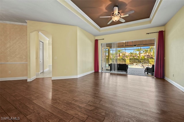 unfurnished room with a raised ceiling, crown molding, wood-type flooring, and ceiling fan