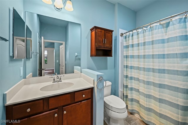 bathroom with an inviting chandelier, vanity, and toilet