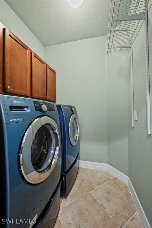 washroom with cabinets, light tile patterned floors, independent washer and dryer, and a textured ceiling