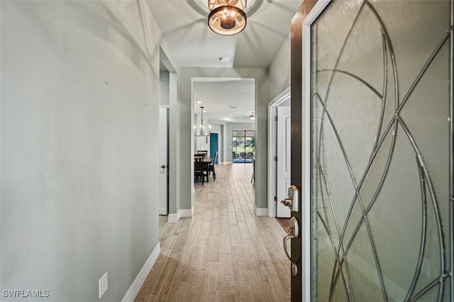 corridor featuring light hardwood / wood-style flooring and a chandelier