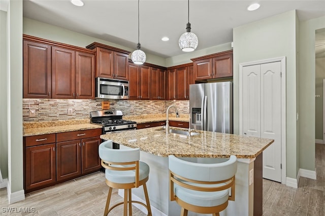 kitchen featuring sink, a kitchen breakfast bar, hanging light fixtures, a kitchen island with sink, and stainless steel appliances