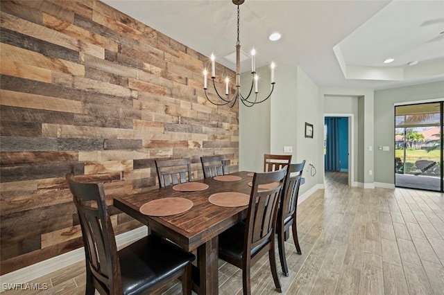 dining space with an inviting chandelier, light hardwood / wood-style flooring, and wood walls