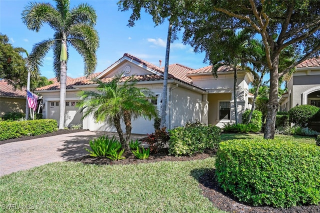 mediterranean / spanish home featuring a garage and a front lawn