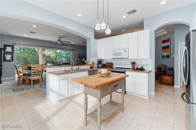 kitchen with sink, stainless steel appliances, white cabinets, decorative light fixtures, and kitchen peninsula