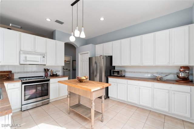 kitchen featuring stainless steel appliances, light tile patterned floors, backsplash, and decorative light fixtures